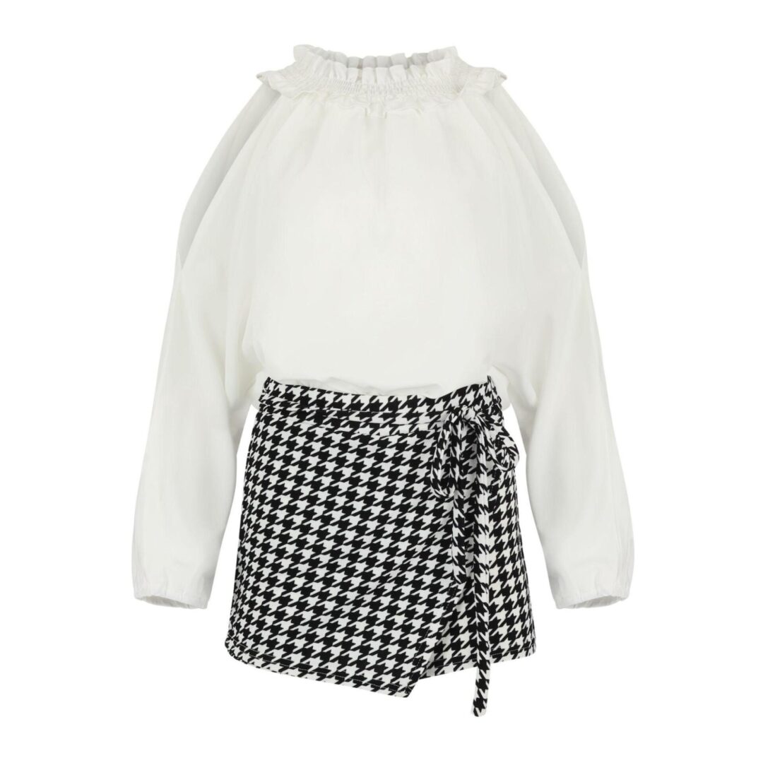 A white top with long sleeves and a black and white skirt.